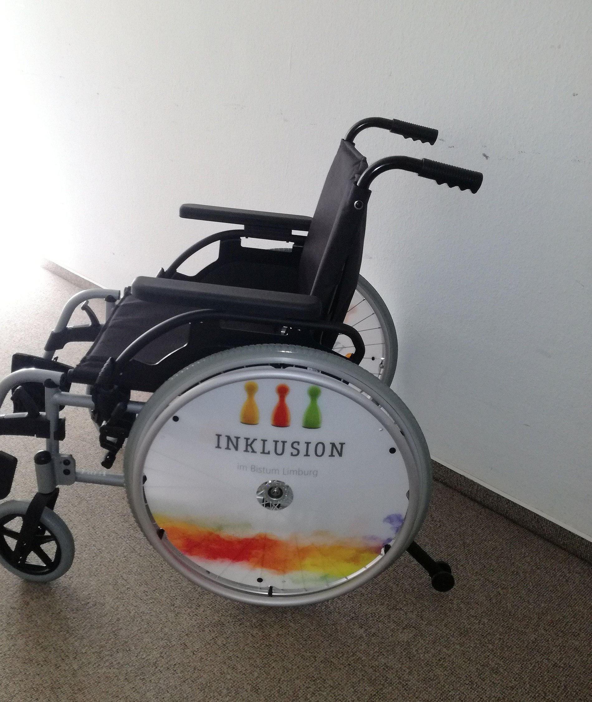 Rollstuhl mit Speichenschutz mit dem Logo der Inklusionsstelle