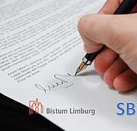 eine Hand untershreibt mit einem Füllfederhalter ein Dokument, darunter sind die Logos der MAV, Bistum Limburg und der SBV