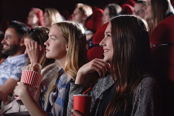 zwei Mädchen mit Popcorn in der Hand schauen einen Film